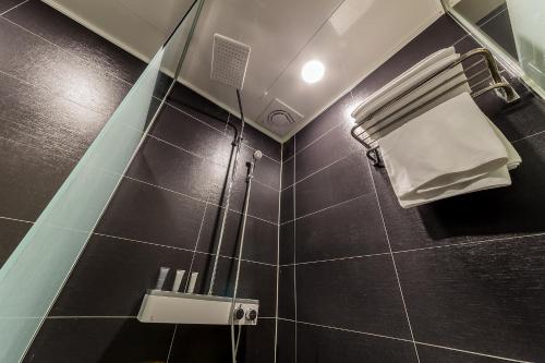 a bathroom with a shower with a black tiled wall at Rosabell Hotel in Ansan