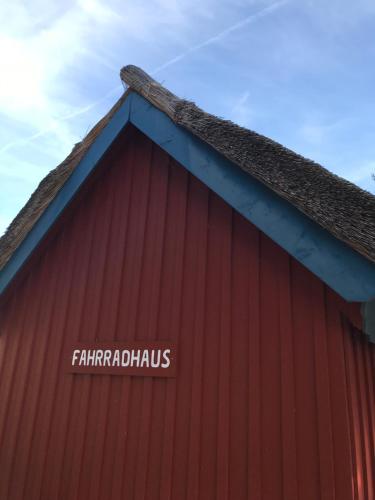 a red barn with a sign on the side of it at "Kapitänshaus" by Ferienhaus Strandgut in Born