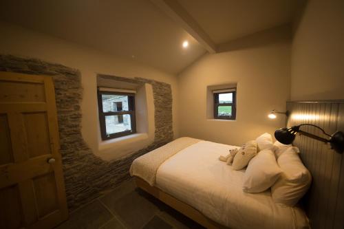 a bedroom with a bed and a lamp and two windows at Elfin Cottage in Doolin