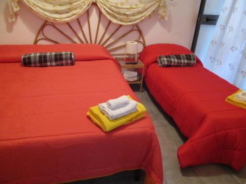 two beds in a room with red sheets at Palazzo Ruisi in Scordia