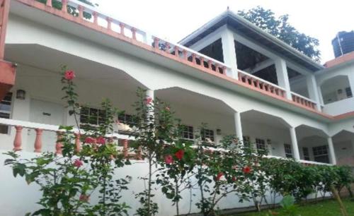 a white building with a balcony with red roses at Polish Princess Guest House in Port Antonio