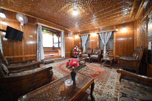 sala de estar con paredes de madera, mesa y sillas en Goona palace houseboats, en Srinagar