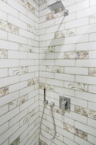 a bathroom with a shower with white brick walls at Rose d'Opera Hotel in Odesa