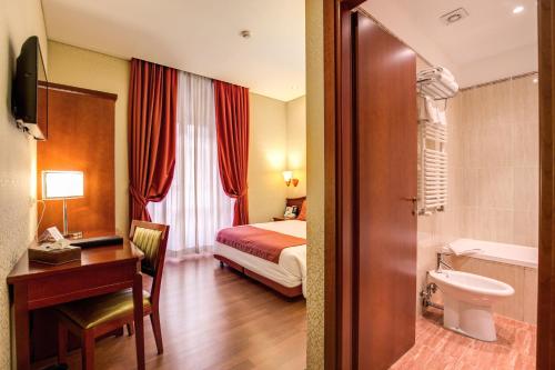Habitación de hotel con cama, escritorio y baño. en Augusta Lucilla Palace, en Roma