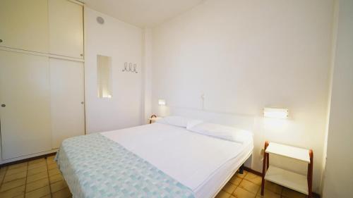 a bedroom with a white bed and a white cabinet at Appartamento Aurora in Lido degli Estensi