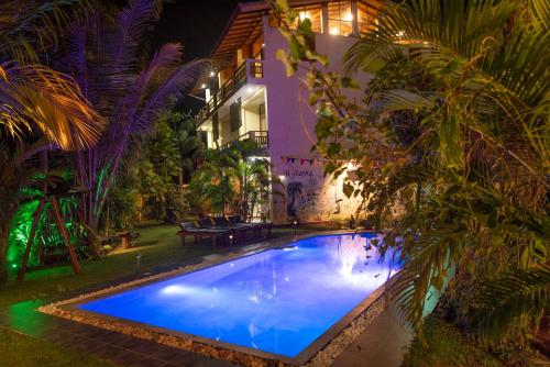 a swimming pool in the yard of a house at night at Hotel Finlanka in Hikkaduwa