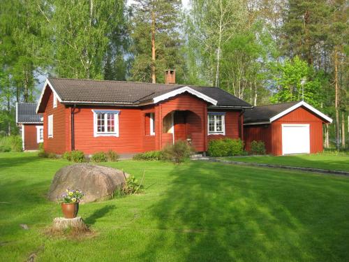 una casa rossa con un grande cortile di fronte di Lilla Huset Oleby a Torsby