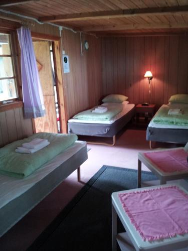 a room with three beds and a table and a lamp at Chokladvillan in Visby