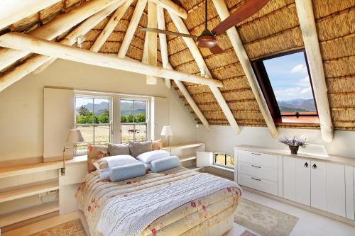 ein Schlafzimmer mit einem großen Bett in einem Zimmer mit Holzdecken in der Unterkunft Villa Simondium in Franschhoek