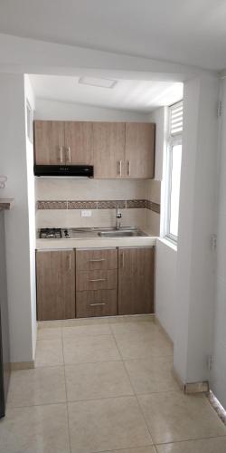 a kitchen with wooden cabinets and a sink and a window at Cavas AP in Cali