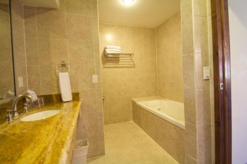 a bathroom with a sink and a tub and a shower at Estancia Inn in Tecate