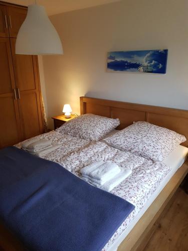 a bed with white sheets and a blue blanket at Nordseeblick Ferienhaus in Wobbenbüll