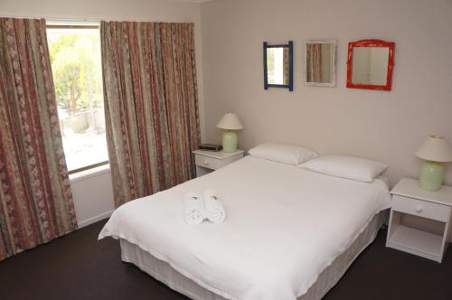 a bedroom with a bed with two white shoes on it at Noosa Sound Resort Noosaville in Noosaville