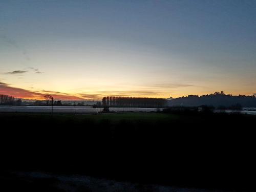 a sunset in a field with the sun setting in the background at Casa degli Orti in Bra