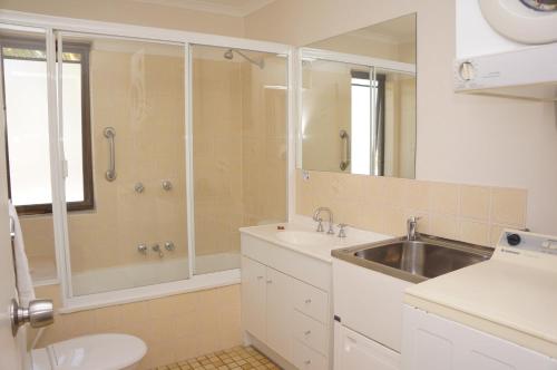 a white bathroom with a sink and a shower at Noosa Sound Resort Noosaville in Noosaville
