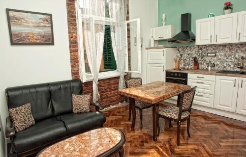 una cucina con tavolo e divano in pelle nera di Apartment Nostalgie a Opatija