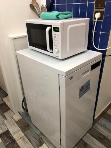 Un four micro-ondes est installé au-dessus d'une armoire blanche. dans l'établissement Brise Lame Face Mer, à Boulogne-sur-Mer