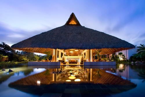 Un complejo con una gran sombrilla de paja y una piscina. en Blue Diamond Luxury Boutique - All Inclusive Adults Only, en Playa del Carmen