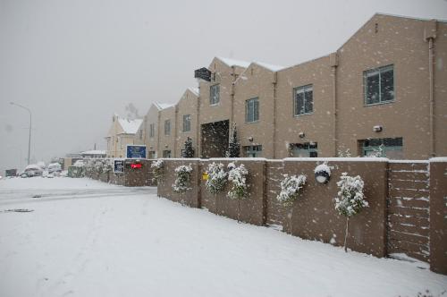 a snow covered street in front of a building at Queenstown Gateway Apartments in Queenstown
