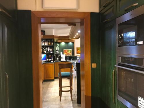 a kitchen with green walls and a bar with a stool at Antik Hotel Sofia in Litomyšl