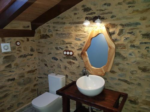 ein Bad mit einem Waschbecken und einem Wandspiegel in der Unterkunft Apartamentos Rurales Casa Carmen in Pola de Allande