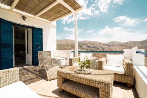 a patio with wicker chairs and a table with a view at Plori Studios and Apartments in Aegiali