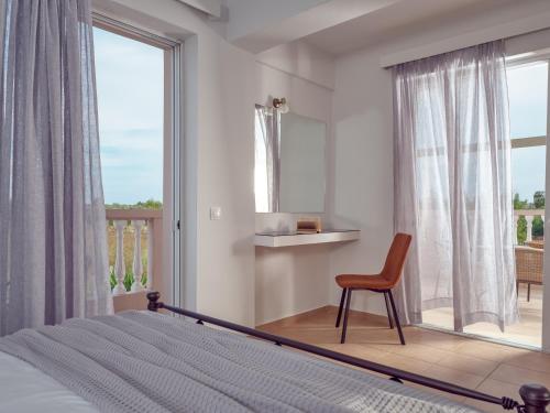 a bedroom with a bed and a chair and a window at Three Graces Holiday Houses Complex in Laganas