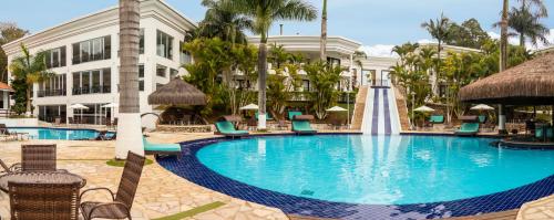 a pool at a resort with chairs and a fountain at Vale Suíço Resort in Itapeva