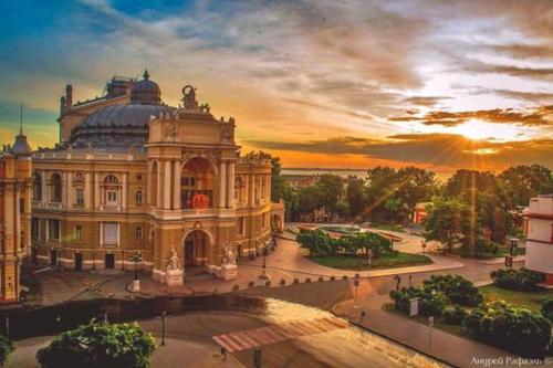 a large building with a sunset in the background at Rose d'Opera Hotel in Odesa