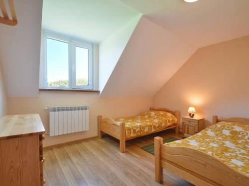 a attic bedroom with two beds and a window at Noclegi u Agatki in Ustrzyki Dolne