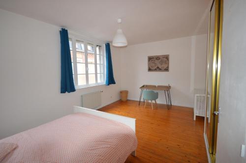 een slaapkamer met een bed, een tafel en een raam bij La Cotonnerie in Saint-Quentin