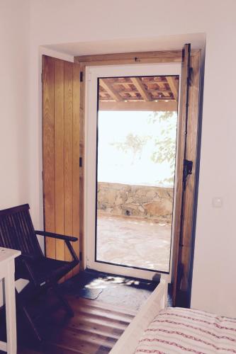 ein Zimmer mit einer Tür, die zu einem Zimmer mit einem Fenster führt in der Unterkunft Casa da Pedra-Quinta do Briando in Portalegre