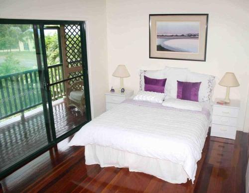 a bedroom with a bed with purple pillows and a balcony at True North B&B in Horseshoe Bay