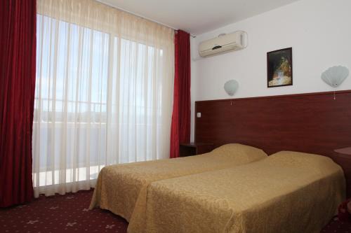 um quarto de hotel com uma cama e uma janela em Ribarska Sreshta Family Hotel em Tsarevo