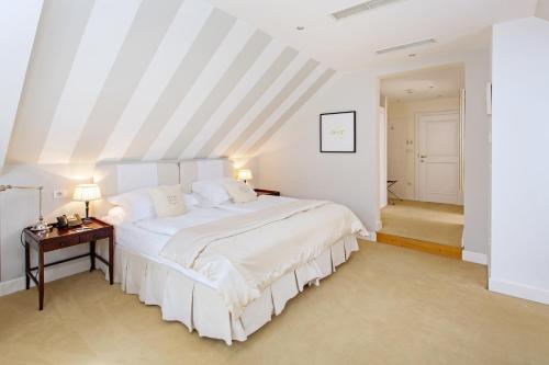 a white bedroom with a bed and a table at Lesar Hotel Angel - Member of Hip Hotels in Ljubljana