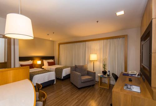 a hotel room with two beds and a couch at Transamerica Executive Faria Lima in Sao Paulo