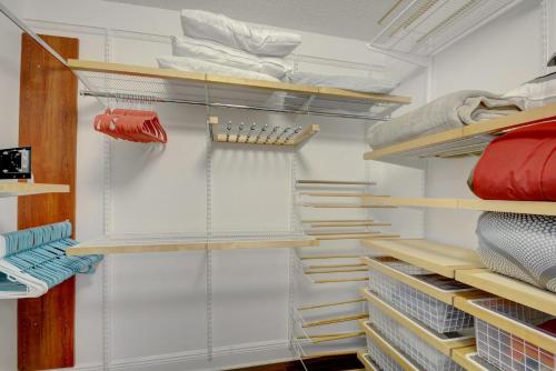 einen begehbaren Kleiderschrank mit weißen Wänden und Holzregalen in der Unterkunft Renovated 2/2 Unit at Yacht Club/Aventura in Aventura