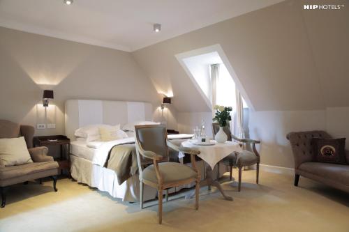 a bedroom with a bed and a table and chairs at Lesar Hotel Angel - Member of Hip Hotels in Ljubljana