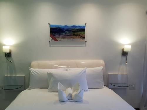 a bed with white pillows and a painting on the wall at Joy Guest House-seapoint in Maseru