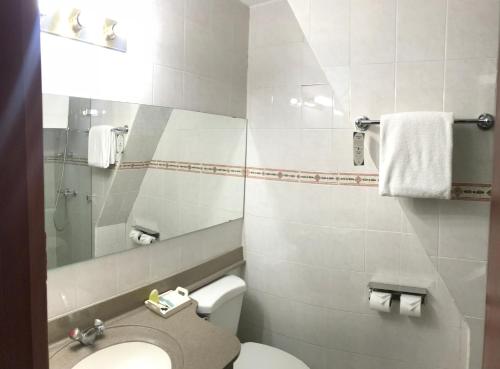 a white bathroom with a toilet and a mirror at Hotel Gardenia Inn in San Salvador