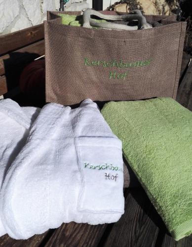 two towels and a bag on a wooden table at Kerschbamerhof im Süden Südtirols in Cortaccia