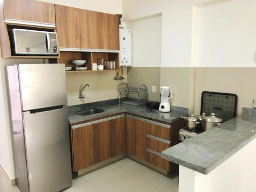 a kitchen with a refrigerator, stove, sink and microwave at Pacifico Apart Hotel in Santa Cruz de la Sierra