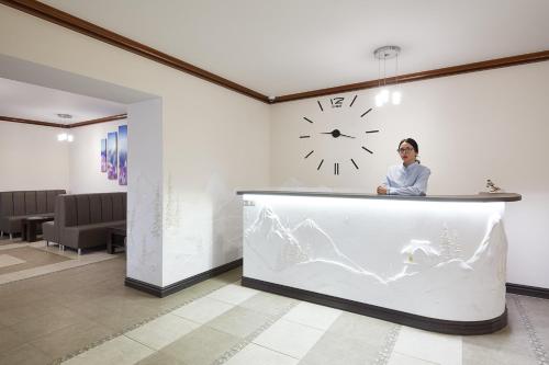 a woman standing behind a counter with a clock at Zaporizʹka Sich in Bukovel