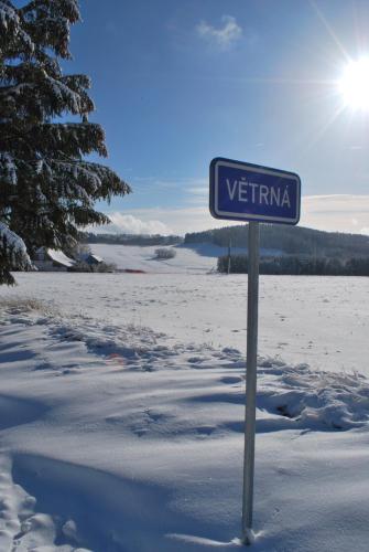 a blue street sign in the snow next to a field at Pokojíky na Větrné in Malšín