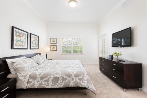 1 dormitorio blanco con 1 cama y TV de pantalla plana en Modern 2 Suites Vacation Apartment RE7659-304, en Kissimmee
