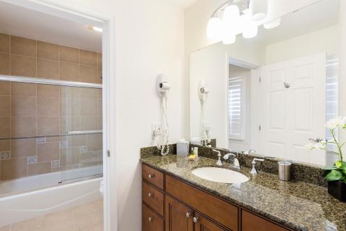 a bathroom with a sink and a mirror and a tub at Modern 2 Suites Vacation Apartment RE7659-304 in Kissimmee
