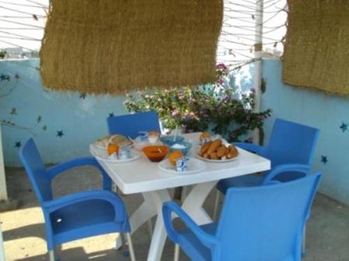 - une table blanche avec des chaises bleues et de la nourriture dans l'établissement Bob Marley House Sherief Hotel Luxor, à Louxor