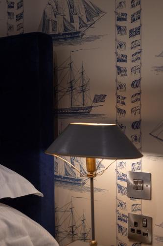 a lamp in a bedroom next to a wall with drawings at The Devonport in Darlington