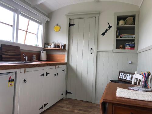a kitchen with white cabinets and a door at The Shepherd's Rest in Oamaru