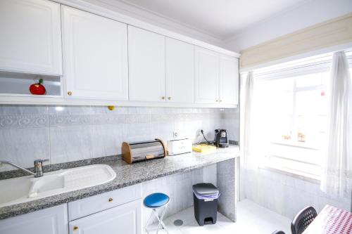 a kitchen with white cabinets and a sink and a window at Apartamento Tejo in Cacilhas